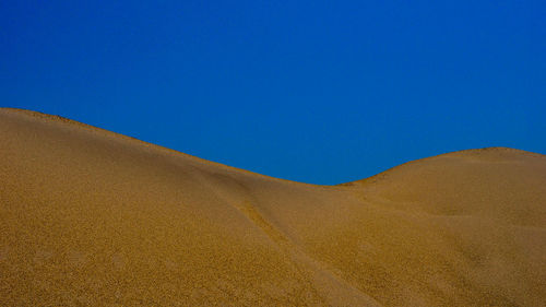 Panoramic view of desert against clear blue sky