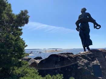 Man standing on rock against sky