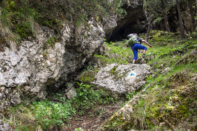 Rear view of man climbing on rock carrying a baby in backpack 