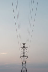 Low angle view of electricity pylon against sky during sunset