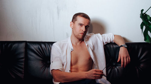 Portrait of young man sitting on sofa at home