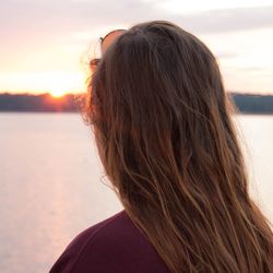 Portrait of woman against lake during sunset