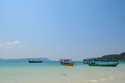 Boats moored in sea against clear sky