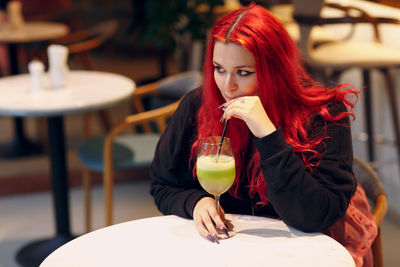 Portrait of young woman drinking glasses on table at cafe