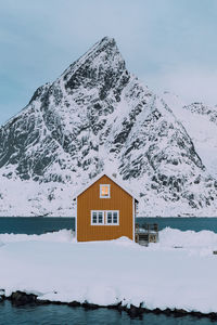 House on snow covered mountain against sky