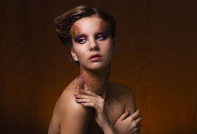 Portrait of shirtless young woman against black background