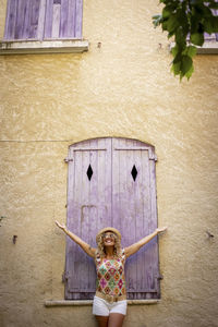 Portrait of a smiling young woman standing against wall