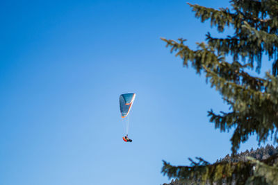 Low angle view of person paragliding against clear blue sky