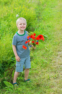 Full length of boy holding red umbrella on field