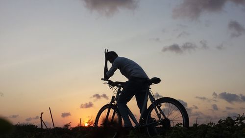 Man cycling against sky during sunset