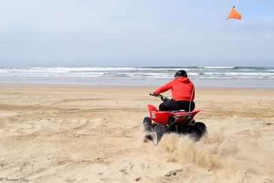 Rear view of person riding quad bike at beach