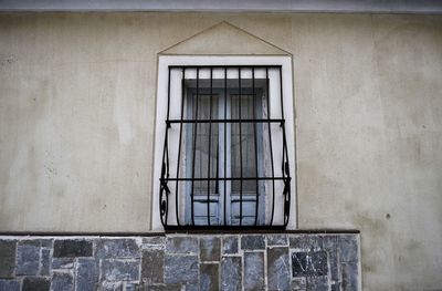 Low angle view of closed window with metal grate on building