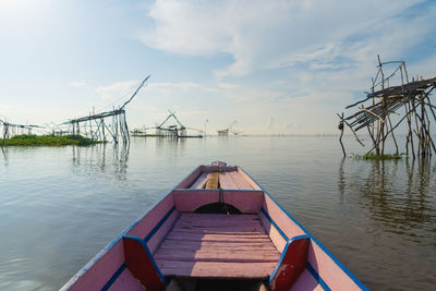 Wooden posts in lake against sky