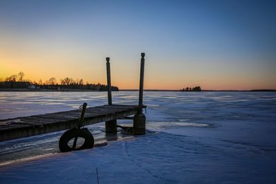 Pier over sea against sky during sunset