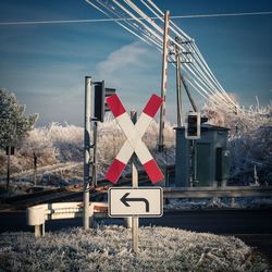 Railroad crossing against sky during winter