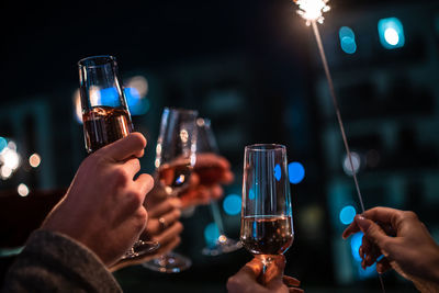 Midsection of people holding glass at night