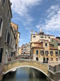 Arch bridge over canal amidst buildings in city