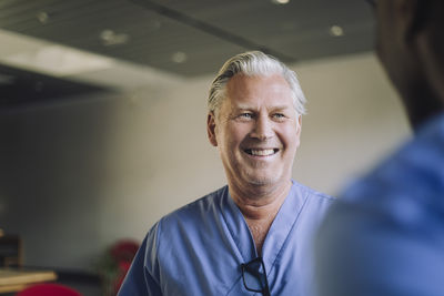 Cheerful senior male physician with colleague in hospital