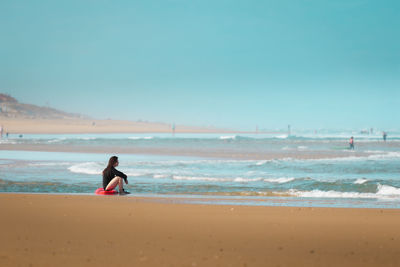 Rear view of woman standing at beach against sky during sunset