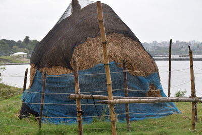 Close-up of thatched roof at beach against sky