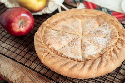 Round apple pie on a wooden background with fresh apples in a canvas bag