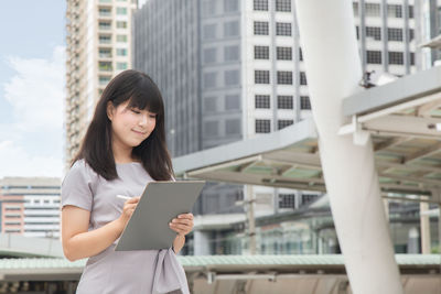 Young businesswoman standing against buildings in city