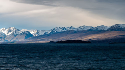 Scenic view of snowcapped mountains by sea against sky