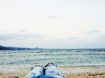 Low section of man on beach against sky