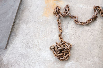
an old chain rusted on the cement floor.