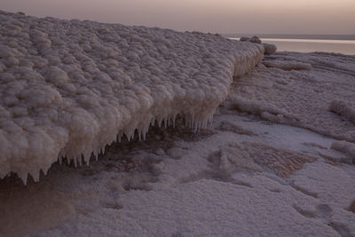 Rocks in sea against sky during sunset