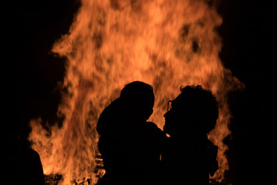 Silhouette father and son against bonfire at night