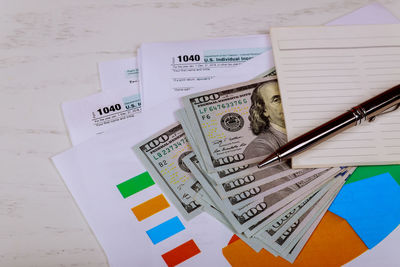 High angle view of pen and book on paper currency at table