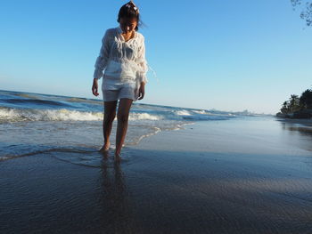 Full length of man standing on beach against clear sky