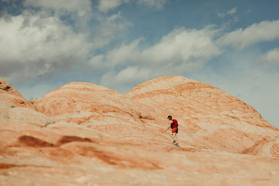 Full length of man climbing rock on land against sky