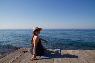 Woman standing at sea shore against clear sky