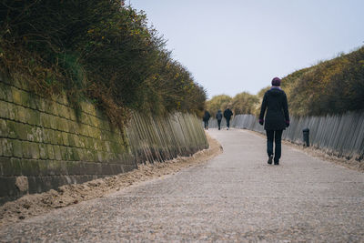Rear view of man walking on footpath