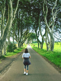 Young woman walking down treelined country road at game of thrones filming location 