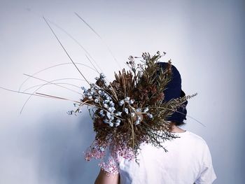 Close-up of woman with bouquet against wall