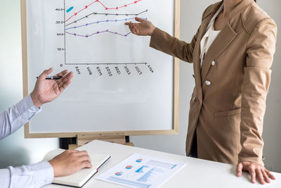 Midsection of businesswoman working with colleague at office