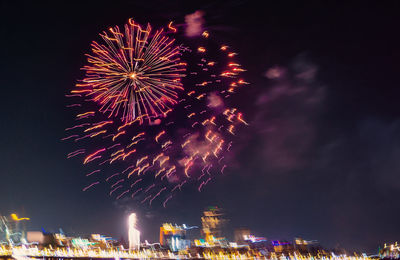 Firework display in city against sky at night