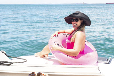 A woman on top of a boat against the sea in the background. 