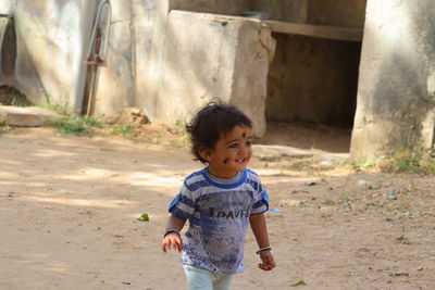 A small child is laughing and walking with black kajal dots on his face 