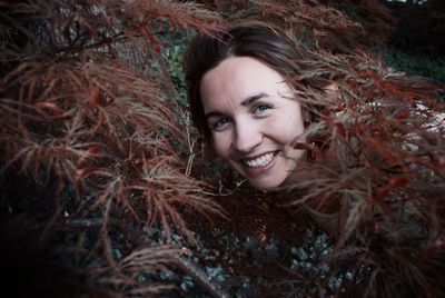 Portrait of smiling woman standing amidst plants at park