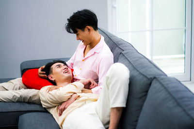 Young woman using mobile phone while lying on bed at home