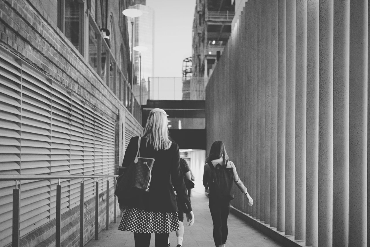 REAR VIEW OF PEOPLE WALKING ON SIDEWALK