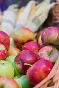 Red ripe apples and corn cobs in a basket at the farmer's market