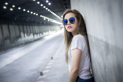 Portrait of woman wearing sunglasses against wall