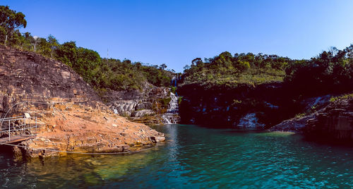 Scenic view of rocks and trees against clear blue sky