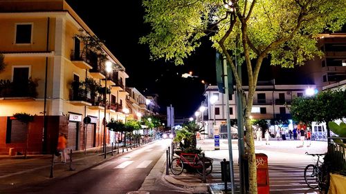 Illuminated street amidst buildings at night