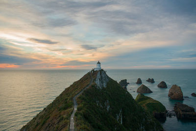 Scenic view of sea against sky during sunset with lighthouse in the center